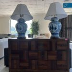 Large brown dresser drawer with two blue and white lamp on top.