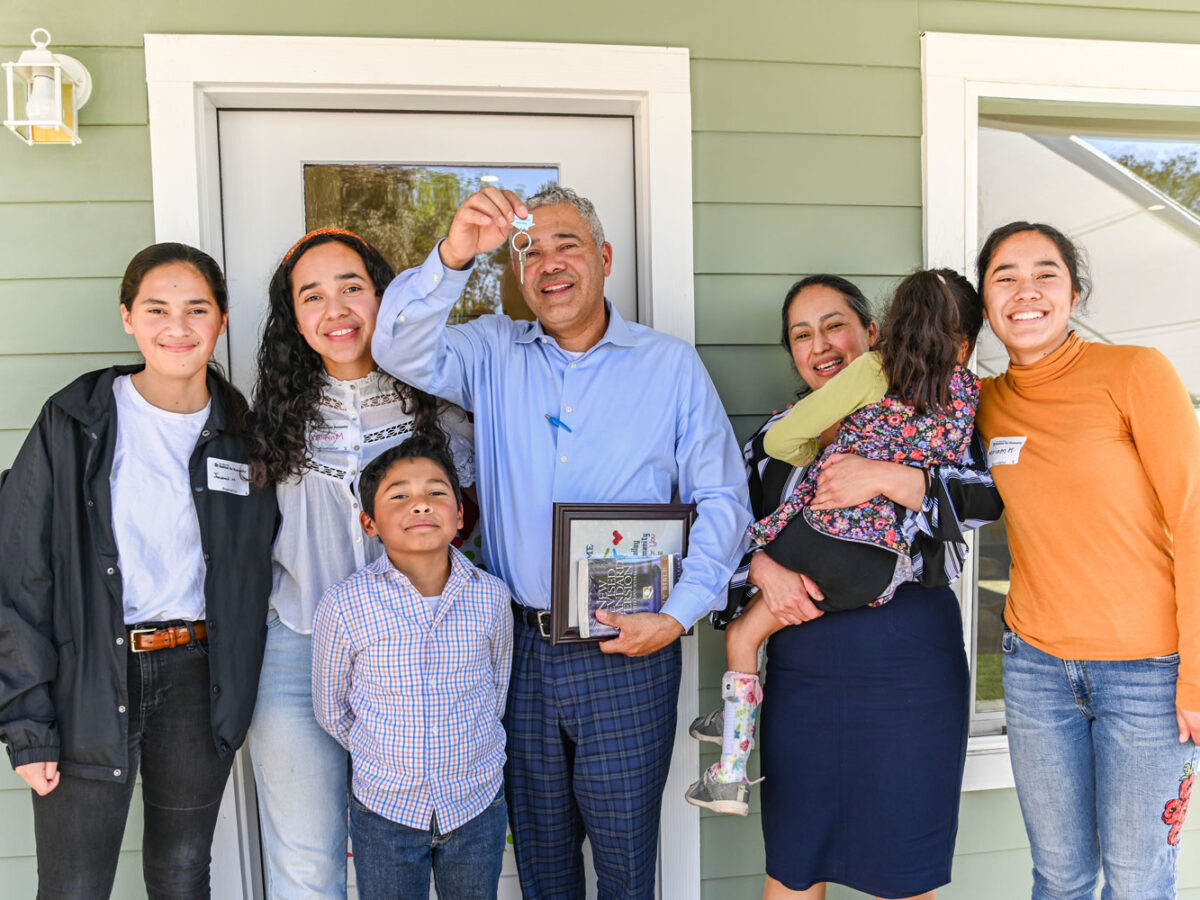 A family on a porch holding a key to their new home.