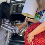 a woman in a striped shirt helping a woman load a lamp and footstool into the back of an SUV