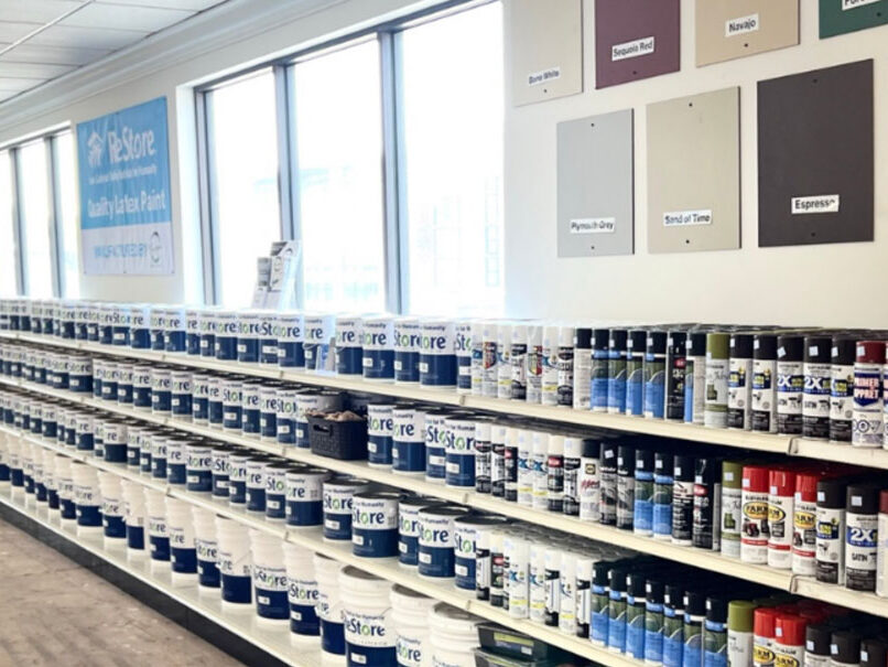 Paint cans and spray paint on shelves in ReStore stores.
