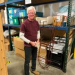 Male volunteer standing smiling and stocking shelves.