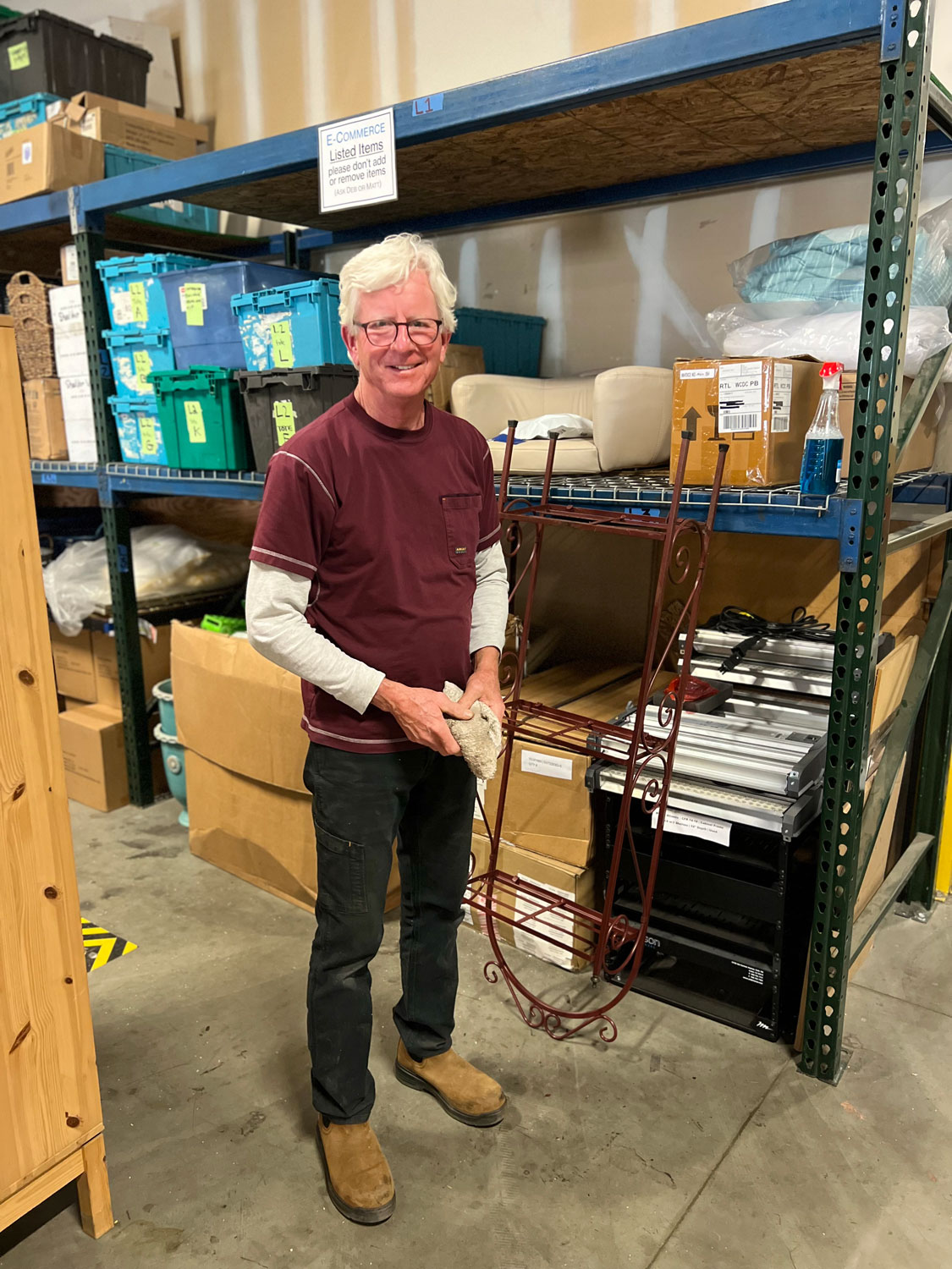 Male volunteer standing smiling and stocking shelves.