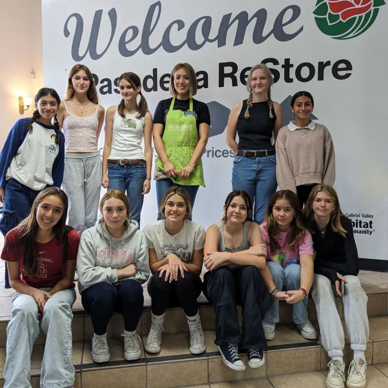 Group of volunteers posing for a picture in front the Pasadena ReStore banner.