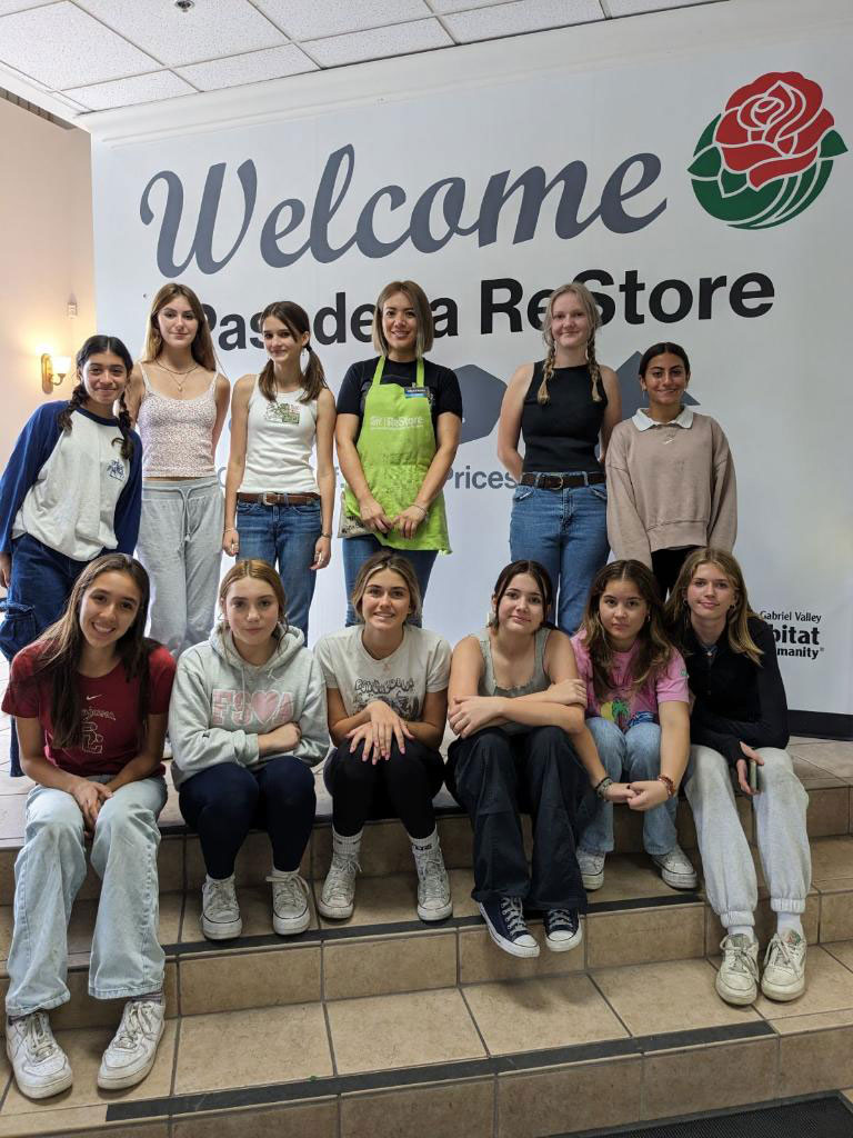 Group of volunteers posing for a picture in front the Pasadena ReStore banner.