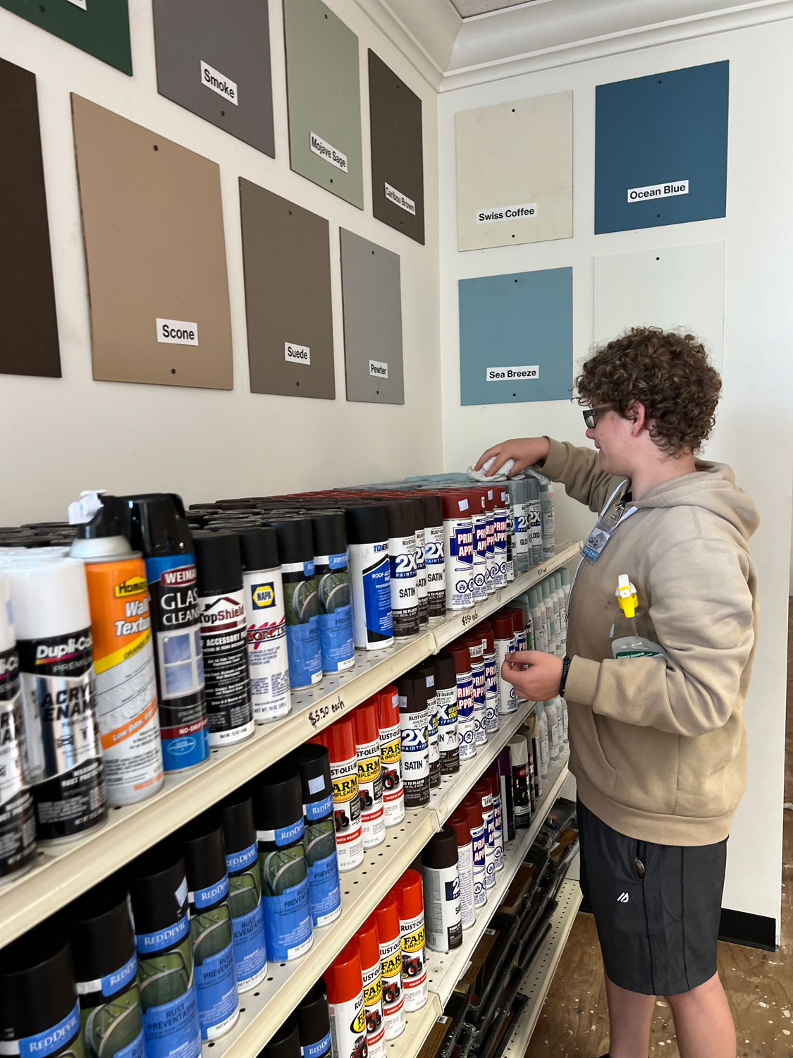 Young man organizing the paint shelves.