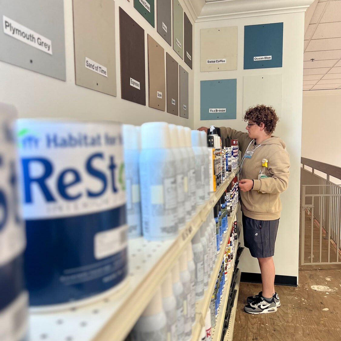 Young man cleaning the paint shelves.