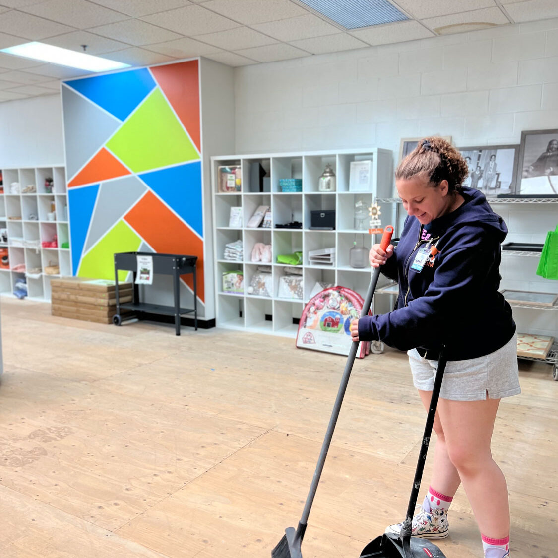 Young lady volunteer sweeping the floor.